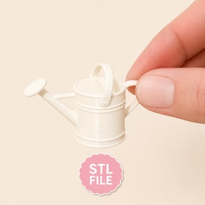 Puede incluir: Una regadera miniatura blanca con un asa curva y un caño, que presenta una pequeña rosa circular en el extremo. Debajo de la regadera hay una insignia circular rosa con bordes festoneados que contiene el texto blanco STL FILE.