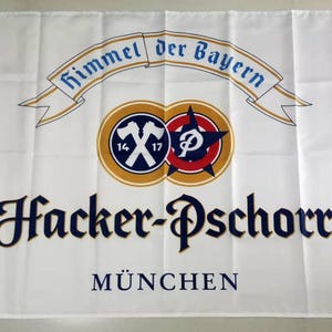 May include: White flag with the Hacker-Pschorr logo, including the text "Himmel der Bayern" and "München". The logo features crossed axes, a star, and a circular design in blue, gold, and red.