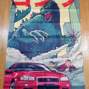 May include: A wall banner featuring a Godzilla illustration. The artwork depicts Godzilla towering over a city, with a red sports car in the foreground. The Japanese text "ゴジラ" is at the top. The color palette includes shades of red, blue, and green.