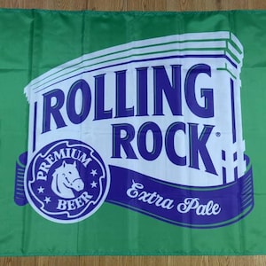 May include: A green flag with a white and blue Rolling Rock beer logo. The logo features a horse head, the words "Premium Beer", and "Extra Pale".