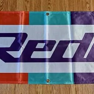 May include: A white banner with a purple, orange, and teal stripe design. The word "GReddy" is printed in large purple letters across the banner.