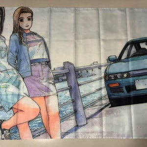 May include: Two women with long, dark hair stand on a bridge with a blue car in the background. The women are wearing colorful clothing and are smiling. The bridge is made of metal and has a wooden railing. The car is a blue sedan with a white stripe down the side.