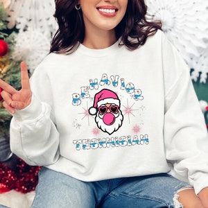 May include: White sweatshirt with a pink and blue Santa Claus graphic and the text "BEHAVIOR TECHNICIAN".