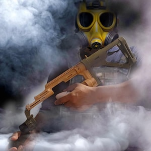 May include: A yellow gas mask and a tan and olive-green toy gun, set against a backdrop of white smoke. The toy gun is held in the hands, and the gas mask has large, circular lenses.
