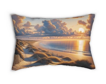May include: Rectangular cushion featuring a beach scene at sunset. The image shows a sandy beach, dunes with tall grass, a wooden fence, and the ocean under a cloudy sky with a bright sun.