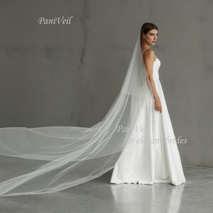 May include: A white wedding veil with a long, flowing train. The veil is made of soft tulle and has a delicate, romantic look. The text "PaniVeil for elegant brides" is visible in the lower right corner of the image.