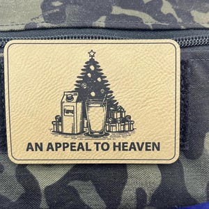 May include: A brown patch with a black and white illustration of a Christmas tree, a glass of eggnog, a carton of eggnog, and presents. The text "AN APPEAL TO HEAVEN" is printed below the illustration.