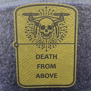 May include: Gold-colored metal patch with a black skull and drone design. The text "DEATH FROM ABOVE" is printed below the design.