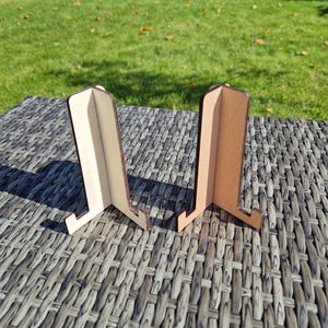 Könnte beinhalten: Zwei Holz-Telefonständer, einer ist hellbraun und der andere dunkelbraun. Beide Ständer sind zusammengeklappt und stehen auf einer gewebten Oberfläche.