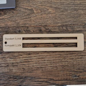 Pu&ograve; includere: Un'etichetta di prezzo in legno con due opzioni: "Standart 0,95&euro;" e "Kompakt 1,10&euro;".