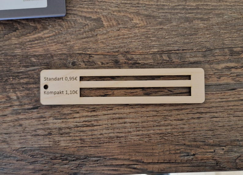 Pu&ograve; includere: Un'etichetta di prezzo in legno con due opzioni: "Standart 0,95&euro;" e "Kompakt 1,10&euro;".