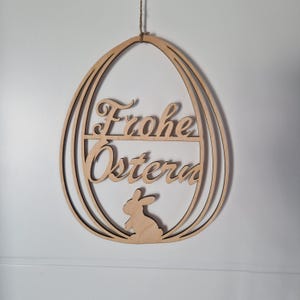 Könnte beinhalten: Ein hölzerner Ostereier-Anhänger mit dem Text "Frohe Ostern" und einer Hasensilhouette.
