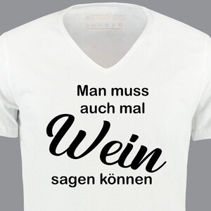 Könnte beinhalten: Weißes V-Ausschnitt-T-Shirt mit schwarzem Text, der "Man muss auch mal Wein sagen können" lautet.