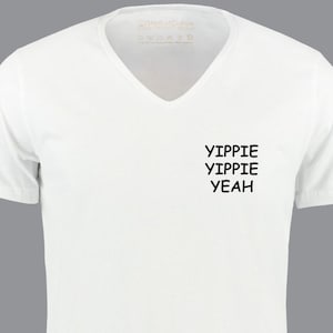 Könnte beinhalten: Weißes T-Shirt mit V-Ausschnitt und dem Aufdruck "YIPPIE YIPPIE YEAH" auf der Vorderseite.