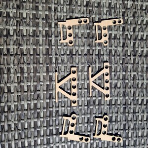 May include: Six light-colored wooden laser-cut components arranged in three pairs. The top and bottom pairs are L-shaped with two circular holes on one arm and three on the other. The middle pair features a triangular brace with five holes.