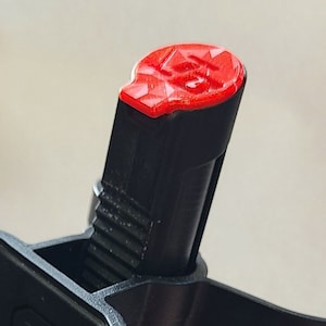 Op de afbeelding: Een zwarte metalen detector spoelhouder met een rode dop aan de bovenkant. De houder heeft een Minelab-logo aan de zijkant.