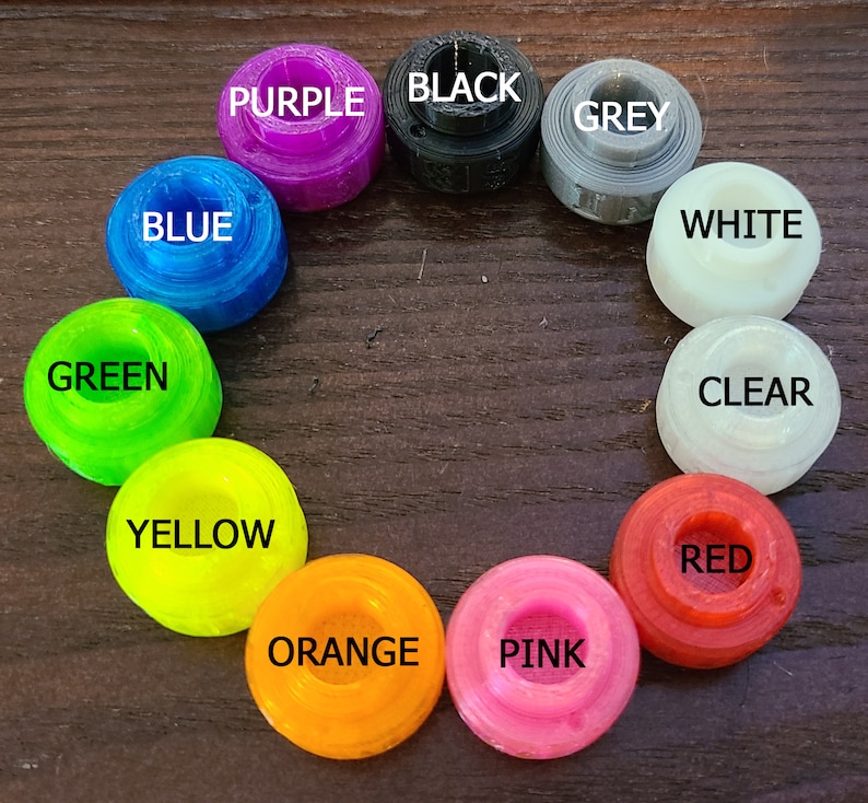 May include: Assortment of 12 colorful round plastic caps with different color names printed on each cap. The colors include purple, black, grey, white, clear, red, orange, pink, yellow, green, and blue.