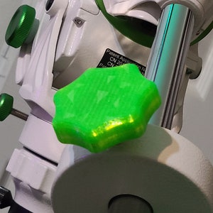 Puede incluir: Primer plano de un pomo verde en forma de estrella en una montura de telescopio blanca y plateada. El pomo es de plástico y tiene una superficie texturizada. El texto "Patent Application No. CN 201..." es visible en la montura.