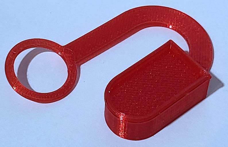 May include: A red plastic hook with a circular opening at one end and a rectangular shape at the other end.