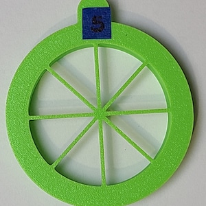 Pode incluir: Um cortador de lima de plástico verde brilhante com oito seções. O cortador tem um pequeno laço na parte superior com a letra "S" escrita em um pedaço de fita azul.