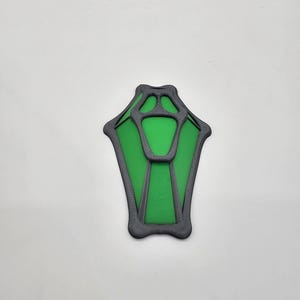 Può includere: Una forma geometrica verde e nera stampata in 3D che ricorda una lanterna o una lampada stilizzata.