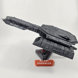 Peut inclure: Un modèle d'un vaisseau spatial imprimé en 3D de couleur grise, le BC-304 Daedalus, sur un support noir avec des accents rouges. Le modèle est détaillé avec des lignes et des textures complexes.