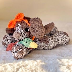 May include: A brown and white crocheted dog toy with an orange bow and a green and yellow crocheted duck toy.