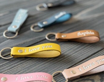 May include: Assortment of leather keychains with different colors and personalized engravings. The keychains feature the phrases "I love you" and "Sophia".