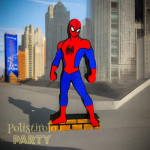 May include: A red and blue Spiderman figurine standing on a brick base. The figurine is made of wood and is painted in a cartoon style. The background is a cityscape.