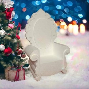 May include: A white, ornate throne chair with a high back and a large, oval seat. The chair is made of foam and has a glittery finish. It is sitting on a snowy surface in front of a Christmas tree.