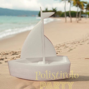 May include: White polystyrene sailboat with a sail and a mast. The sailboat is sitting on a sandy beach with palm trees in the background.