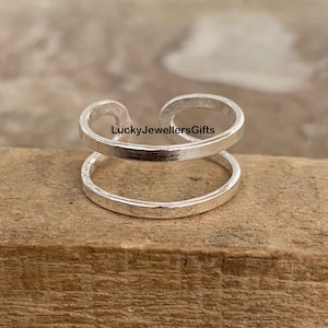 Puede incluir: Pendiente de oreja doble de plata. El pendiente de oreja está hecho de dos anillos de plata que están conectados entre sí. El pendiente de oreja es una pieza de joyería popular que se puede usar en cualquier ocasión.