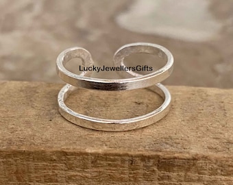 May include: Silver double ring ear cuff. The ear cuff is made of two silver rings that are connected together. The ear cuff is a popular piece of jewelry that can be worn on any occasion.