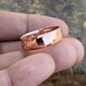 May include: A simple, polished copper band ring. The ring is a classic style and has a smooth, shiny finish.