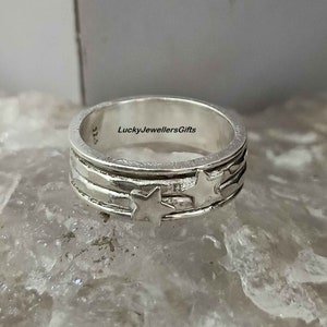 Op de afbeelding: Een zilveren ring met een getextureerde band en vijf stervormige uitsparingen. De ring is gemarkeerd met "925" en "LuckyJewellersGifts".
