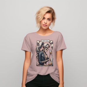 May include: A mauve colored t-shirt with a graphic of a skeleton woman in a leather jacket drinking from a glass. The graphic also includes skulls and the text "HAPPY HOUR".