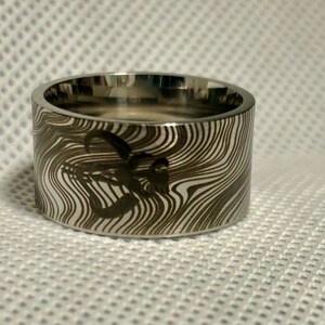 Pu&ograve; includere: Un anello d'argento con un motivo unico, a spirale, bianco e nero. L'anello &egrave; largo e ha una finitura lucida.