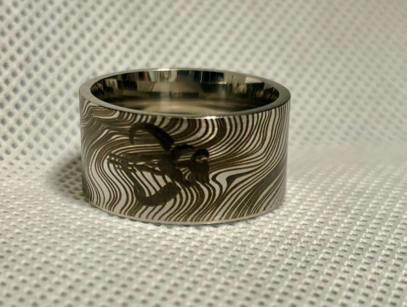 Pu&ograve; includere: Un anello d'argento con un motivo unico, a spirale, bianco e nero. L'anello &egrave; largo e ha una finitura lucida.