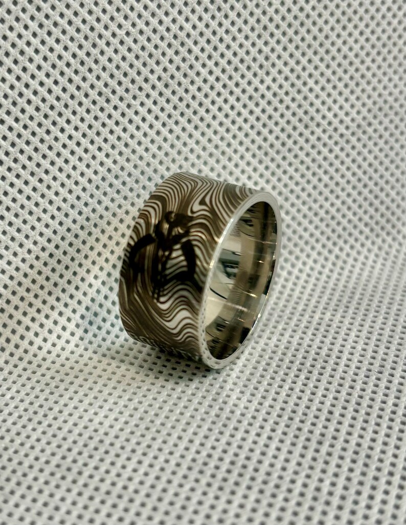 Pu&ograve; includere: Un anello d'argento con una fascia a motivi bianco e nero. Il motivo &egrave; un design a spirale.