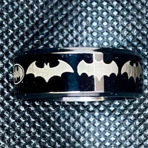 Personalized superhero bat inspired ring, inside and outside wrap around various symbols through the years.