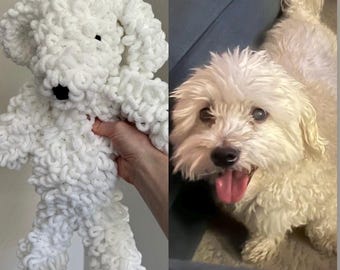 Puede incluir: Un juguete de peluche de perro blanco tejido a crochet y un perro blanco sentado en un sofá gris.