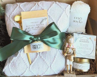 Caja de regalo navideña blanca: manta, tés negros, popurrí para estufa, adorno de cascanueces y vela.