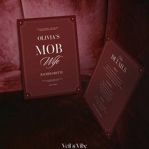 May include: A burgundy red invitation with gold trim for a bachelorette party. The invitation reads "Olivia's Mob Wife Bachelorette" with the location "Aspen, Colorado". A second card with the same burgundy red color and gold trim lists the details of the event.
