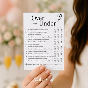 May include: A printable bridal shower game card with the title "Over or Under" and a list of 14 questions about the bride and groom. The game asks guests to guess if the answer to each question is over or under a certain number.  The card has a heart symbol and a section for guests to add their name and score.