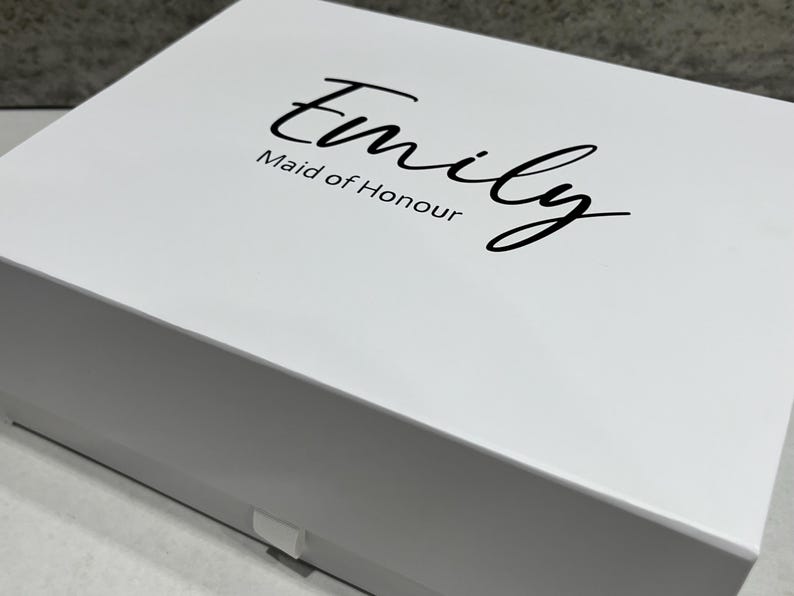 May include: White gift box with a black inscription that reads "Emily Maid of Honour".