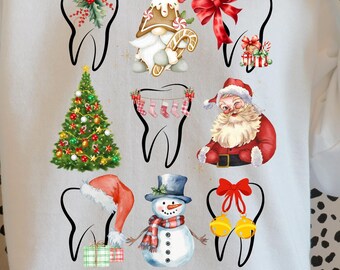 以下が含まれることがあります： 白いスウェットシャツ。歯の形にクリスマスツリー、サンタクロース、雪だるまなどのクリスマス要素が組み込まれたお祝いの歯科テーマのデザイン。スウェットシャツは人が着ています。