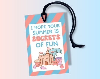 May include: A pink and blue striped tag with a black string. The tag has a cartoon illustration of a sandcastle, waves, and buckets. The text on the tag reads "I hope your summer is buckets of fun."