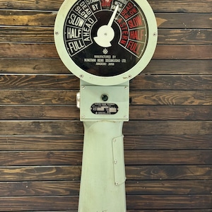 May include: A vintage mint green ship's telegraph, featuring a circular dial with speed and direction indicators. The dial displays "Ahead," "Astern," and speed settings. The base is marked "Manufactured by Nunotani Keiki Seisakusho Ltd, Amagasaki Japan."
