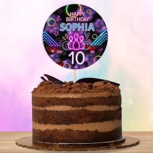 Puede incluir: Un adorno redondo para pastel con un diseño de brillo neón. El adorno presenta un gráfico de bolos y bola de bolos, el texto "Happy Birthday Sophia" y el número "10".