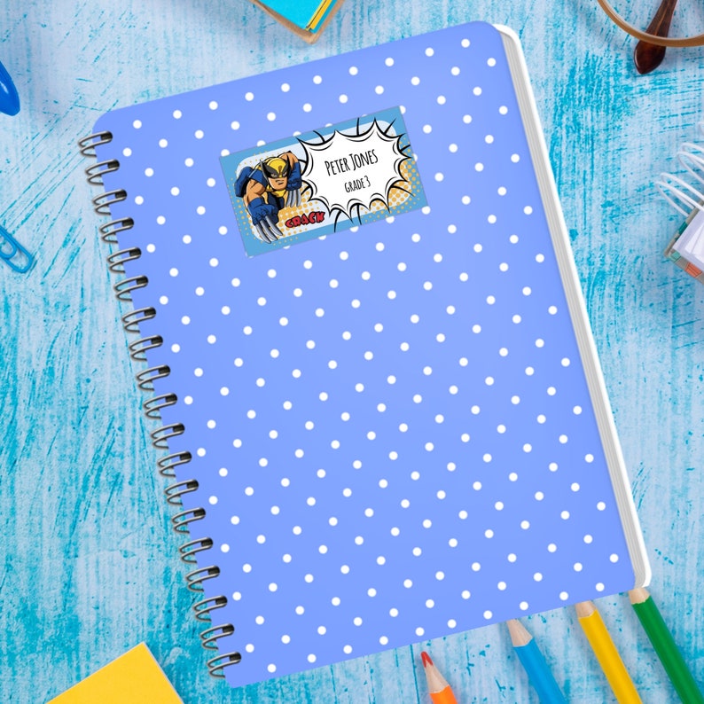 May include: A blue notebook with white polka dots and a colorful sticker with the text "Peter Jones Grade 3" and a cartoon superhero image.